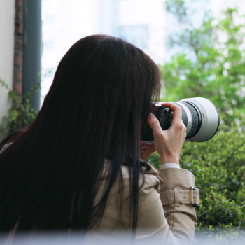 Woman taking a photo with a dslr camera equipped with a telephoto lens.