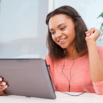 Woman smiling while using a tablet with headphones.