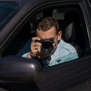 A man taking a photo from the driver's seat of a car.