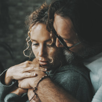 Man embracing a woman in a comforting manner.