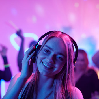 Young woman wearing headphones enjoying a party with colorful lighting.