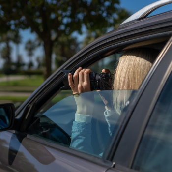 Woman taking a photo from inside a car.